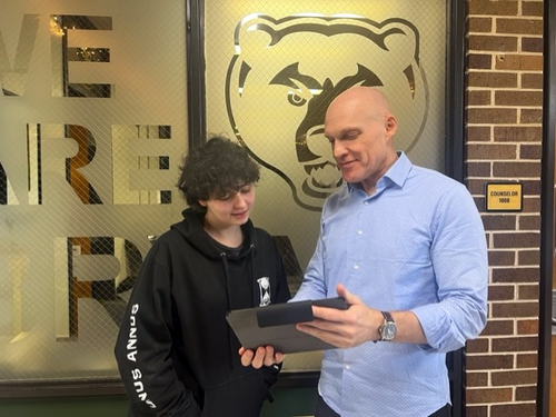 A counselor and student look at a tablet